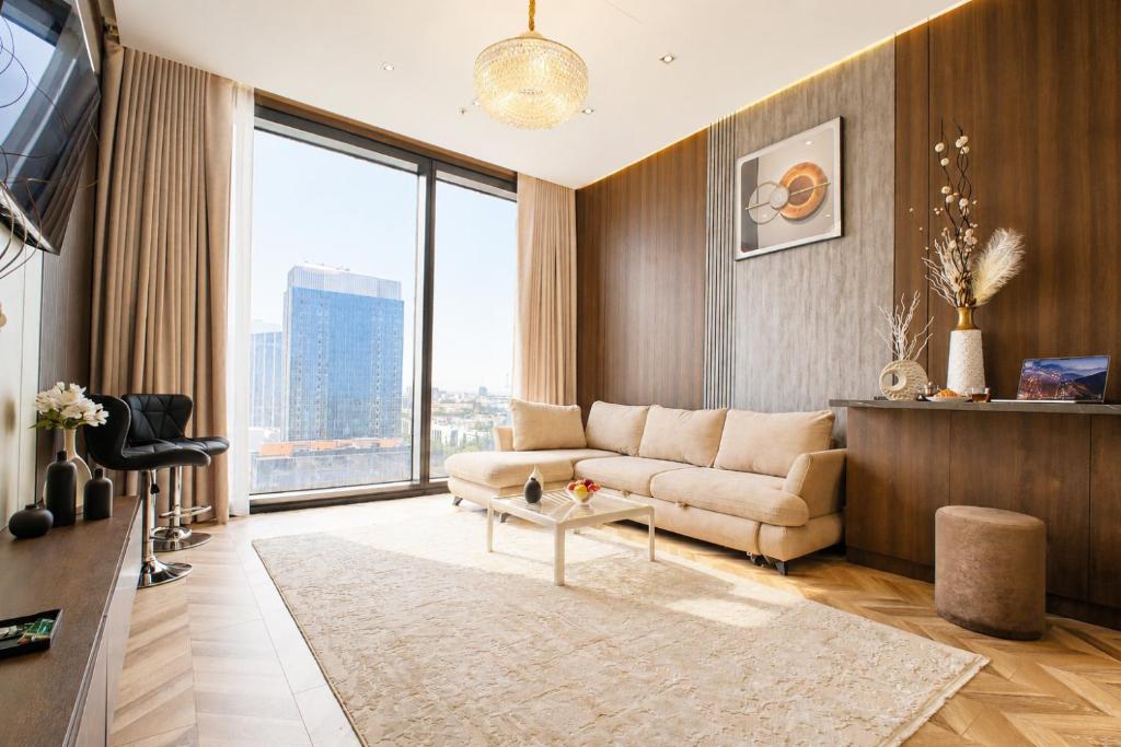 a living room with a couch and a large window at NOVA HOME Apartments - NEST ONE, Panoramic Views, Tashkent City in Tashkent