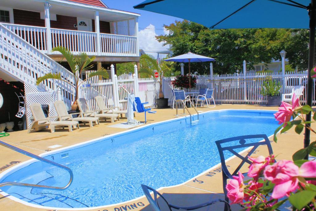 einen Pool mit Stühlen und einem Sonnenschirm in der Unterkunft The Burgundy Inn Hotel and Apartments in Ocean City