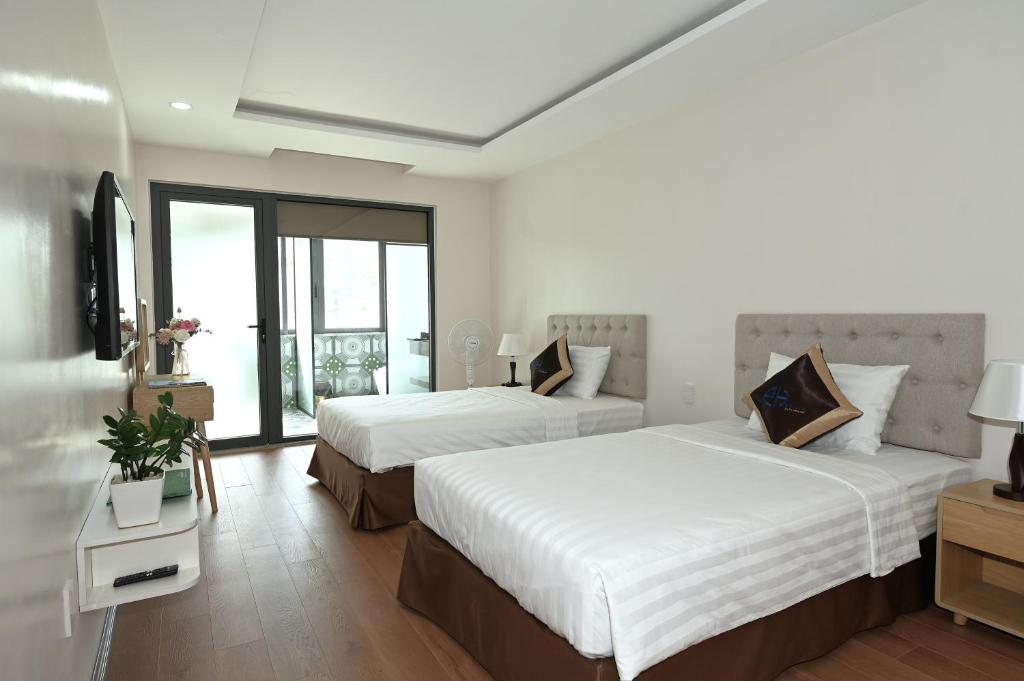 a hotel room with two beds and a television at EcoHouse Boutique Hotel Huế in Hue