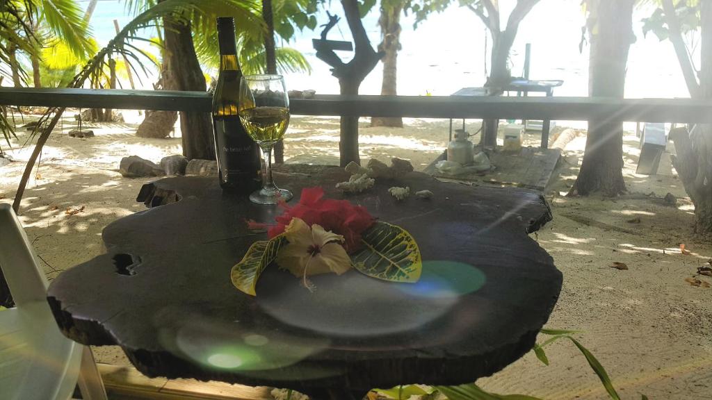a table with a glass of wine and flowers on it at Matriki Beach Huts in Arutanga