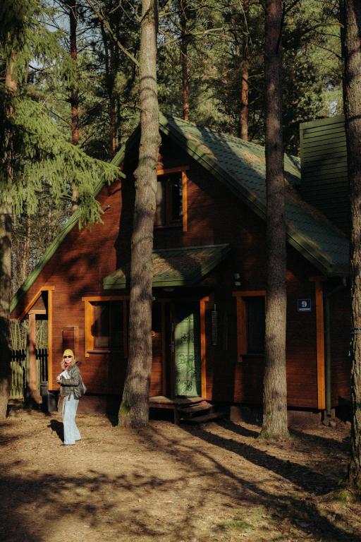 a woman standing in front of a log cabin at Jarzębinowa - artystyczny dom na Podlasiu in Łuka
