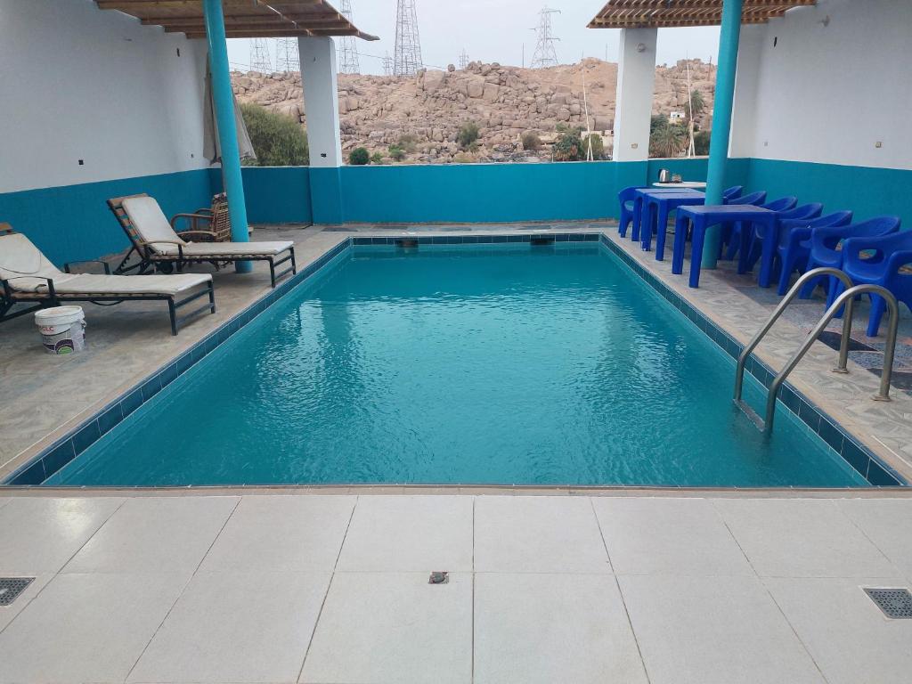 a swimming pool with chairs and a blue wall at Ashria gest house in Jazīrat Salūjah