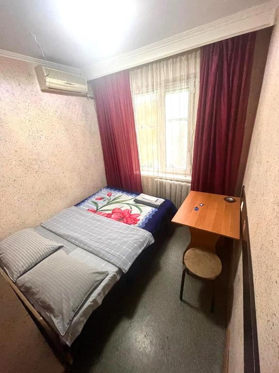 a small room with a bed and a table at Гостиница Гулдер in Almaty