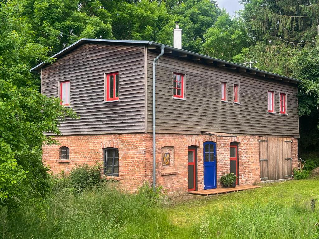 an old brick house with red windows and a blue door at Gästescheune Rubitz in Rubitz