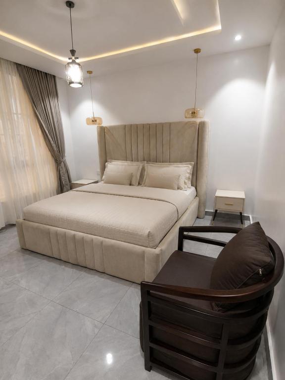 a bedroom with a large bed and a chair at 5and6 Apartments in Abuja