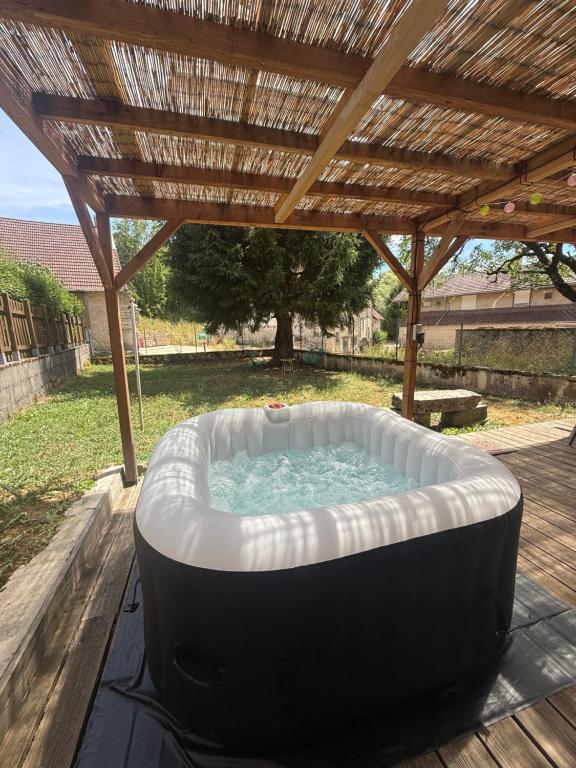 a hot tub sitting under a wooden pergola at Gite du sapin - Lac de Vouglans - SPA Privatif in Orgelet