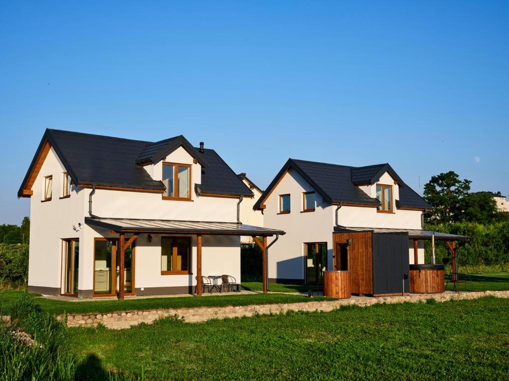 a large white house with black roof at Domki Różane Nad Stawem in Stopnica
