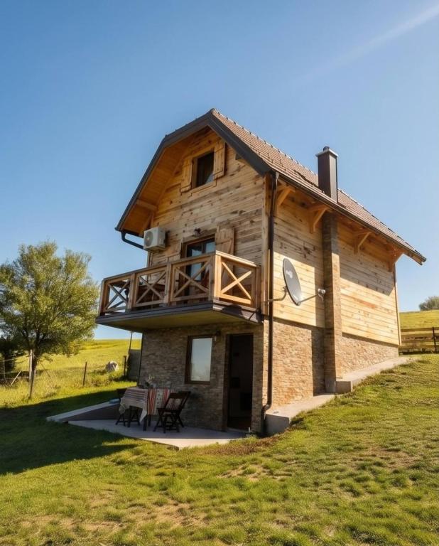 a large wooden house with a wrap around porch at Brvnara K2 KONAK in Šljivovica