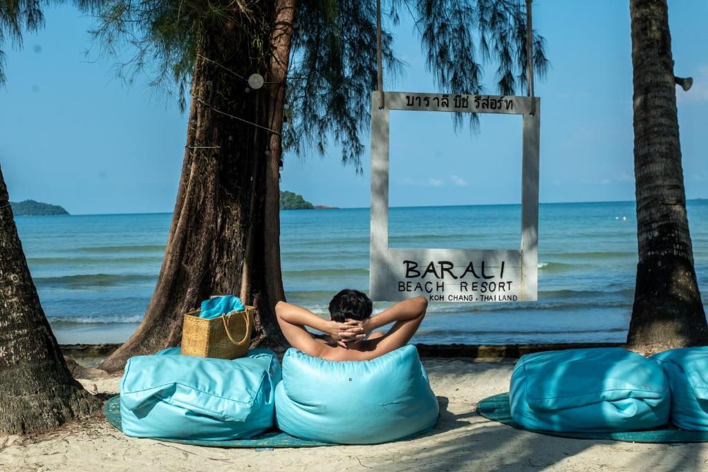 a man sitting on a bean bag on the beach at Barali Beach Resort Koh Chang in Ko Chang