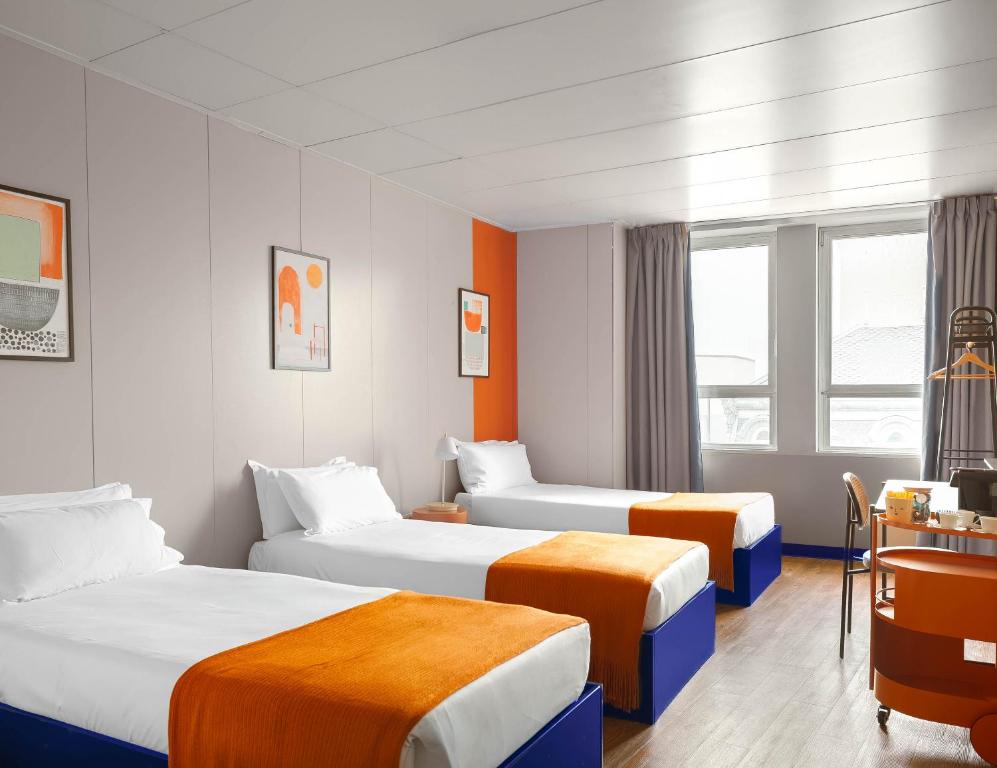 a hotel room with two beds and a desk at STAYSOME Porto Herculano in Porto