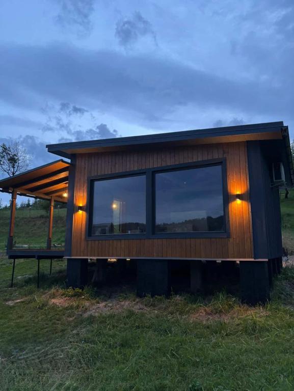 a house with a large window in a field at Pletey house in Verkhovyna