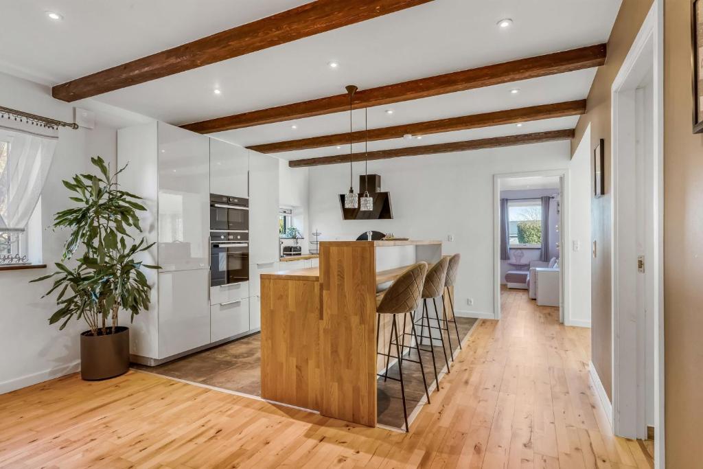 a kitchen with white cabinets and a bar with stools at Seaside Home in Fakse Ladeplads