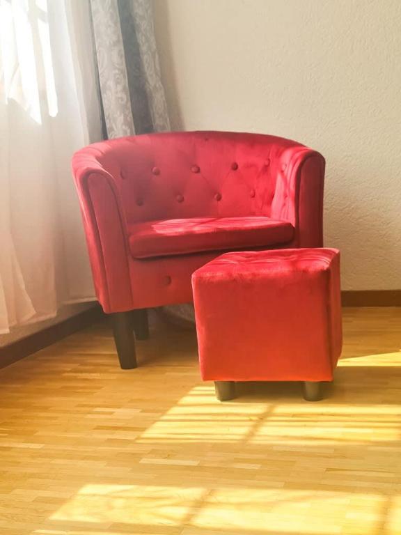 a red chair and a stool in a room at Sofia Apartment - Aare Jungfrau AG in Wilderswil