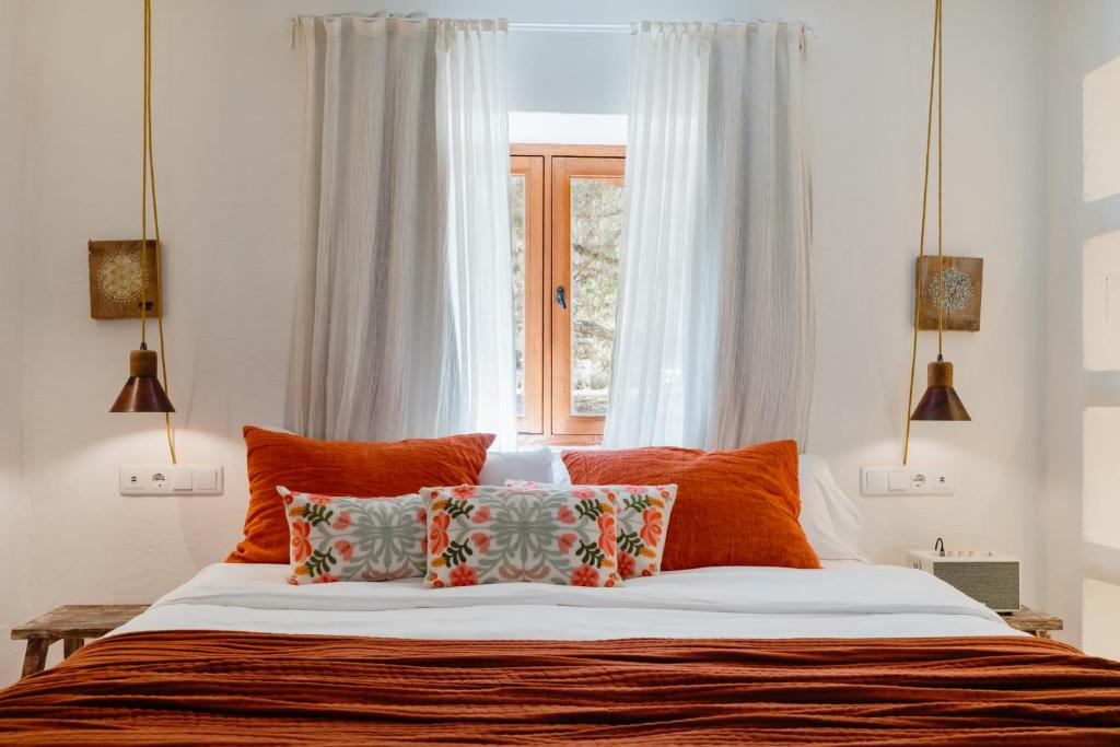 a bed with orange pillows in front of a window at Can Vistabella Boutique Resort in San Antonio