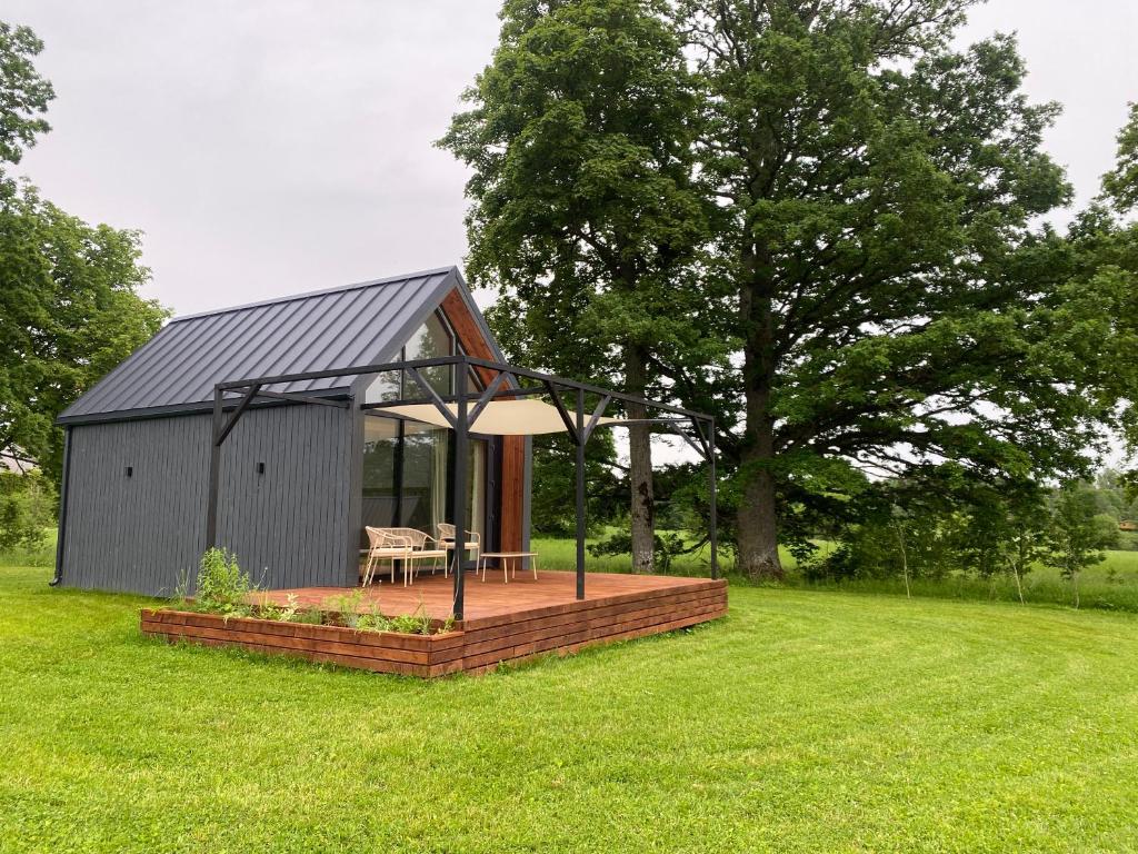 a small cabin with a deck in the grass at Atpūtas vieta Kannas in Tropmači