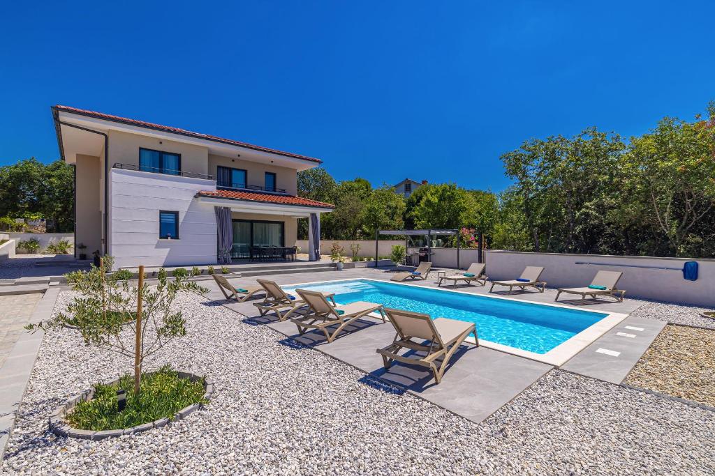 a swimming pool with chairs and a house at Villa ADRIA MOMENTS with private pool in Pinezici
