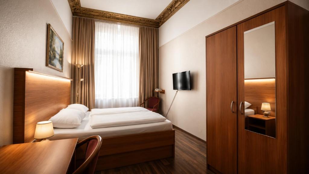 a bedroom with a bed and a desk and a window at Hotel AI Königshof in Berlin