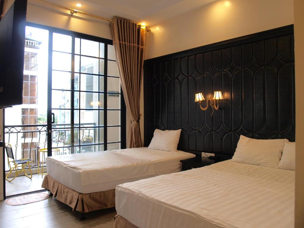 a hotel room with two beds and a large window at Ánh Sao in Ha Long