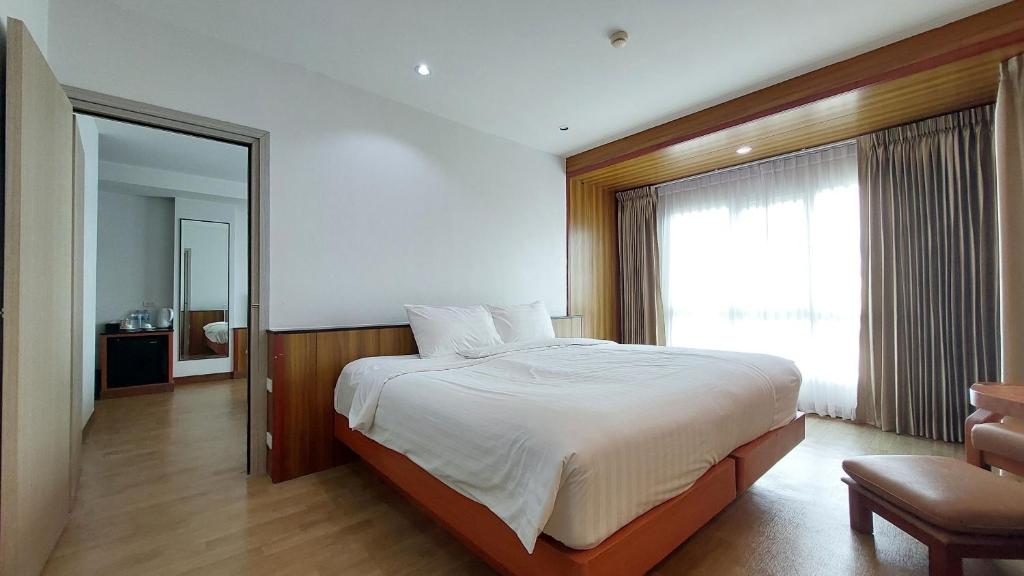 A large-bed room with a bright curtained window and warm wood detailing.