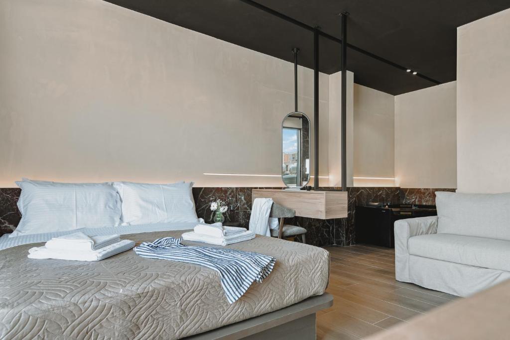 a bedroom with a bed and a couch and a chair at MAHA Her City Living by Semavί in Heraklio