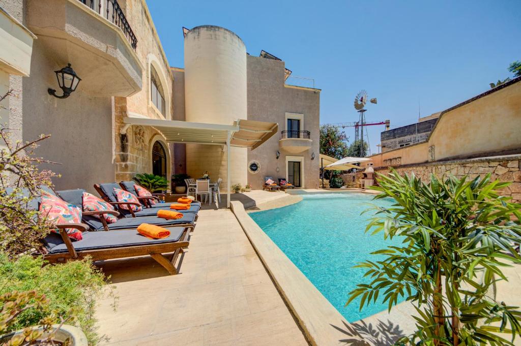 a backyard with a swimming pool with lounge chairs next to a house at Valleyside Heights Residence - Pool & Heated Jacuzzi in Is-Swieqi