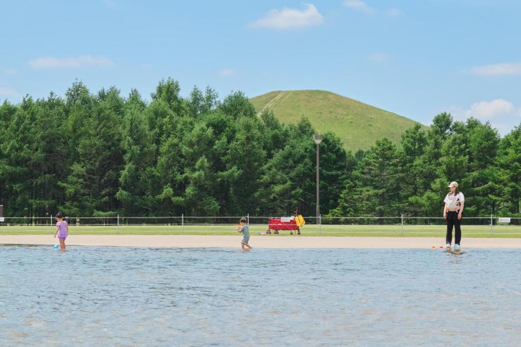 a woman and two children standing in the water at 藤乃宿 Villa Moere モエレ沼公園すぐ 愛犬と一緒に泊まれる新築1棟貸し in Sapporo
