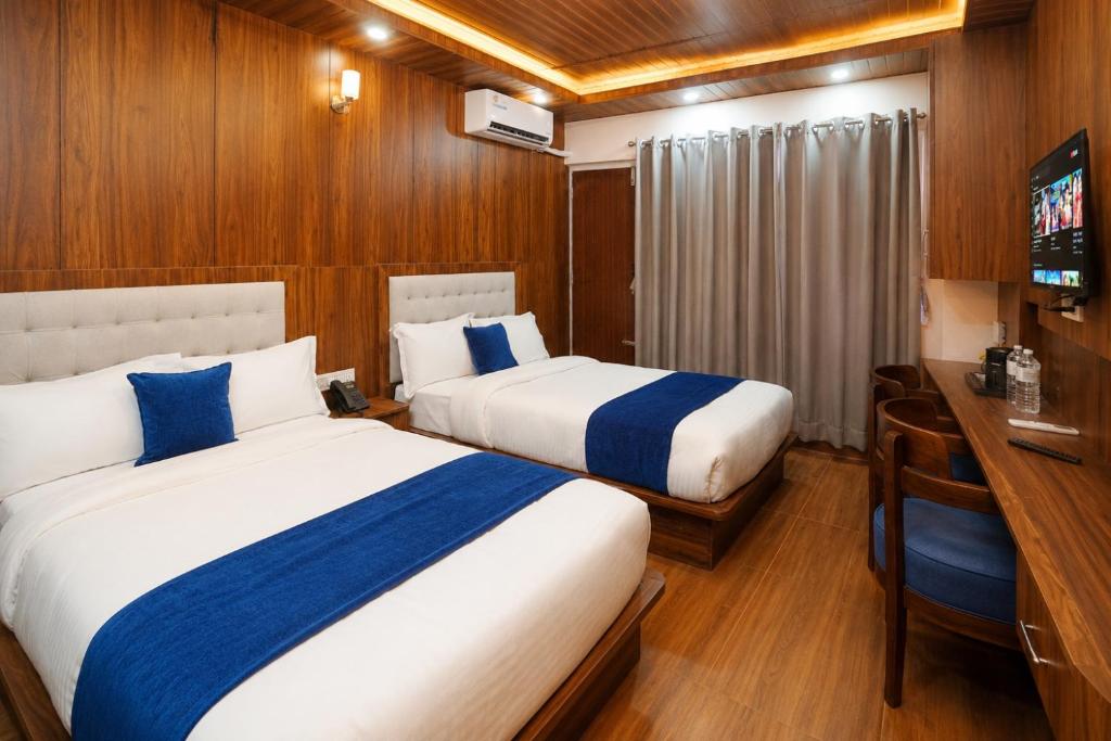 a hotel room with two beds and a desk and a television at Hotel happy stay inn in Pashupatināth