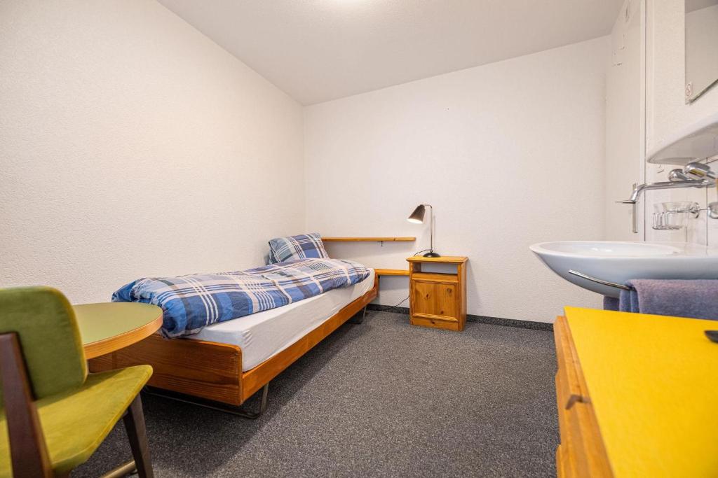 a bedroom with a bed and a sink in it at Hotel Haus am Wald in Arosa