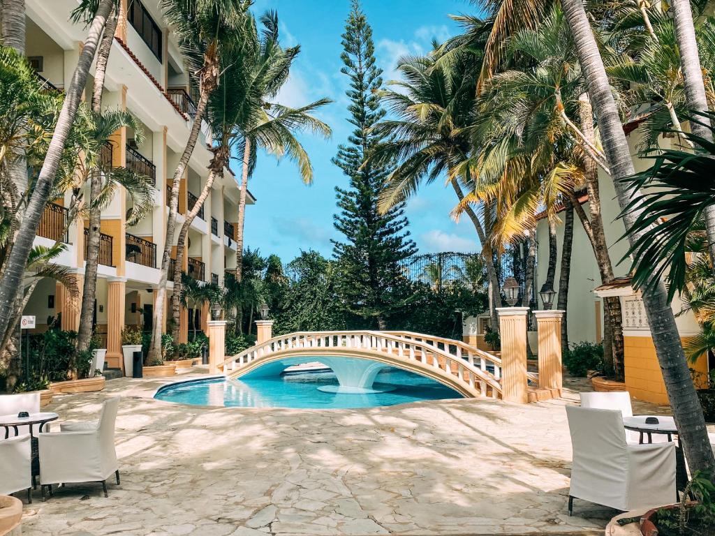 a bridge over a pool at a hotel with palm trees at Hotel Plaza Brisas in Punta Cana