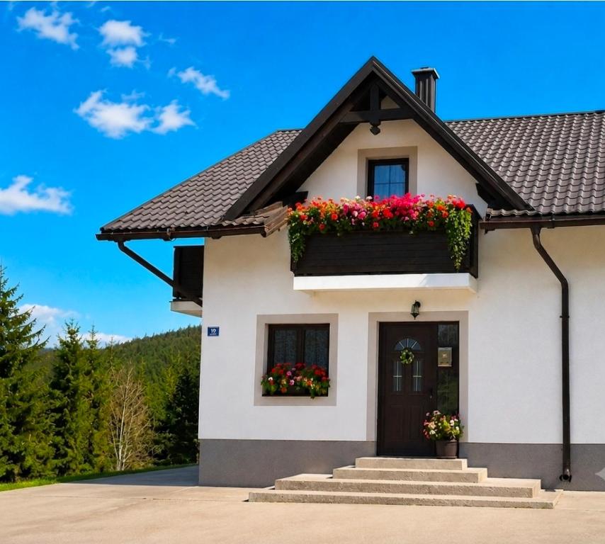 a white house with flower boxes on it at Apartman Malnar Lokve in Lokve