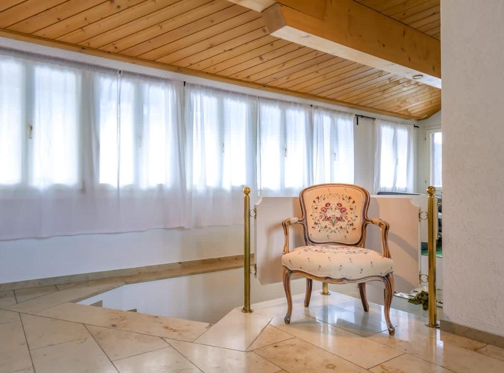 una sedia seduta in una stanza con una finestra di Chalet Weid - Aare Jungfrau AG a Grindelwald