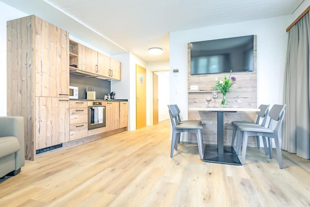 a living room with a table with chairs and a tv at Lauberhorn Apartment - Aare Jungfrau AG in Grindelwald