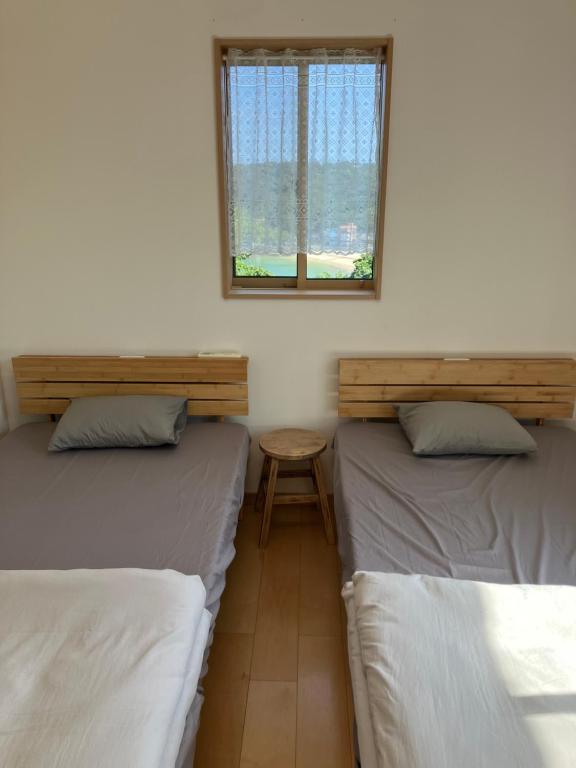 two beds in a room with a window and a table at Ocean view Private Hotel in Shimoda