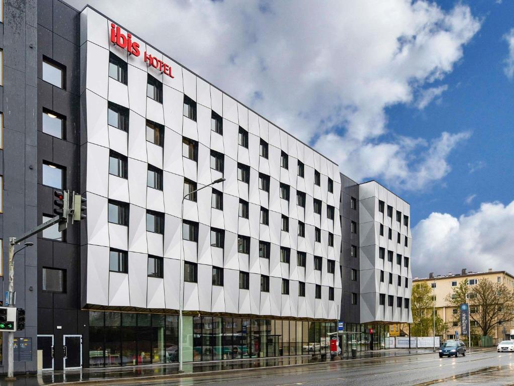 a white building with a red hotel sign on it at ibis Tallinn Center in Tallinn