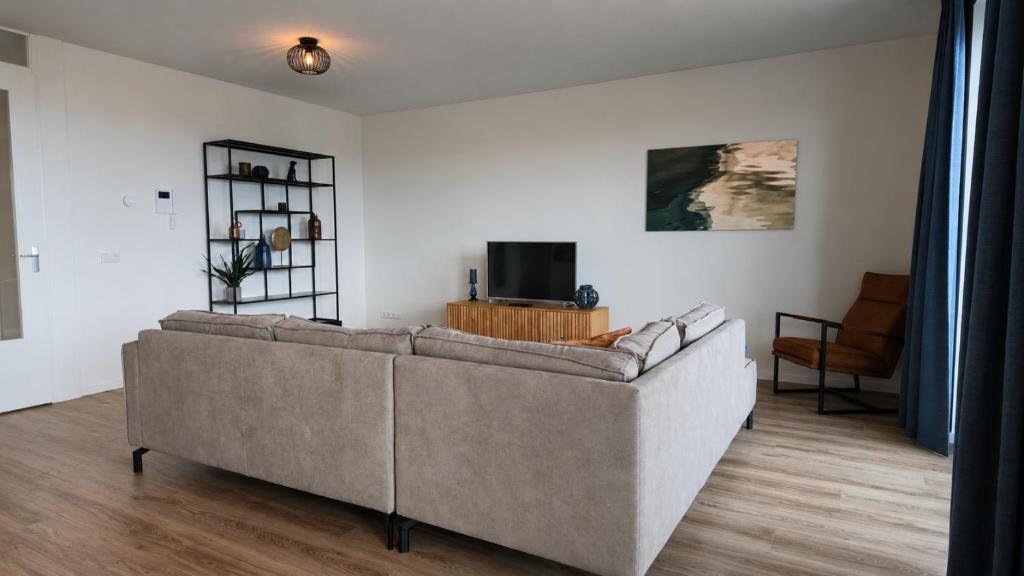 a living room with a couch and a tv at Residentie De Zeester | 4 Pers. De Zeester in Scherpenisse