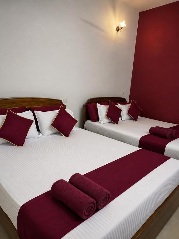 two beds in a room with red and white at French Garden Eagle Wings Inn in Trincomalee