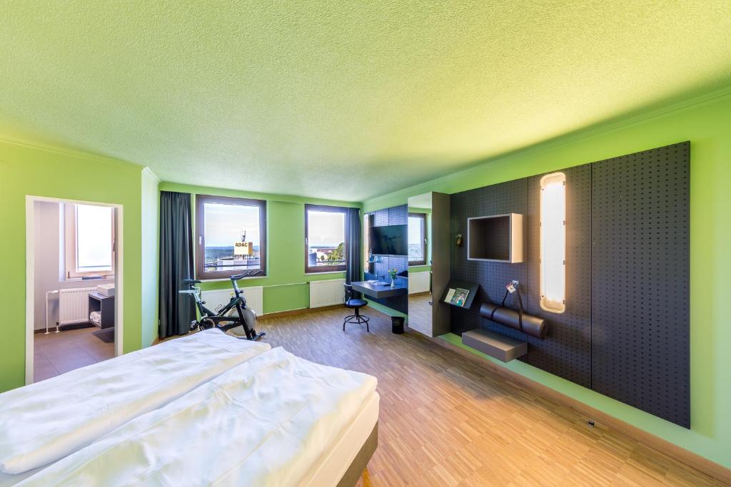 a bedroom with green walls and a bed and windows at mk hotel remscheid in Remscheid