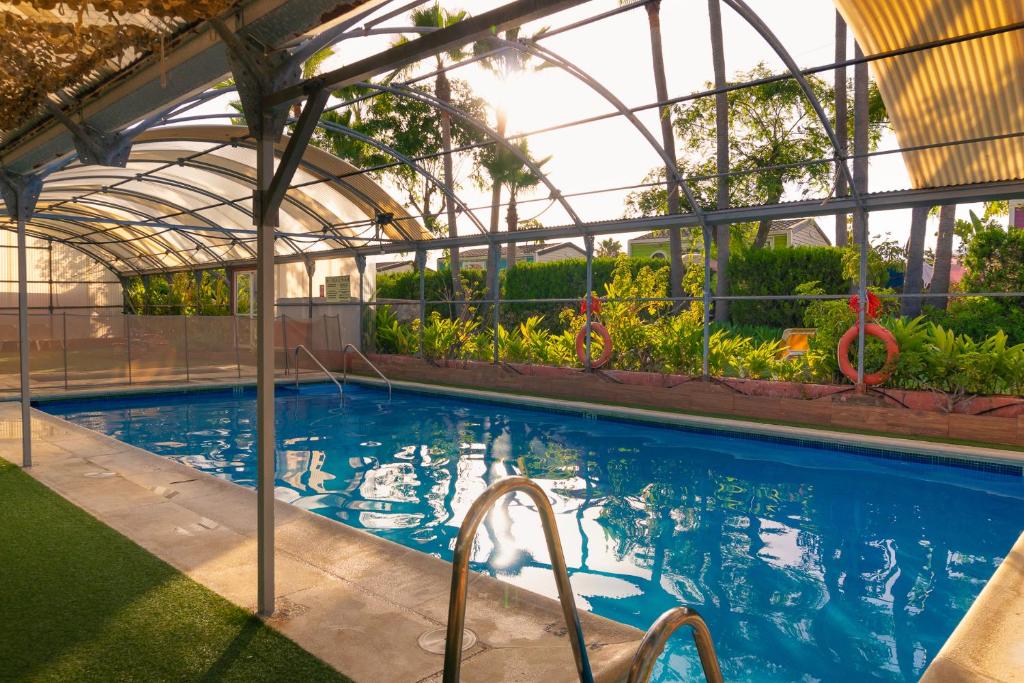 a swimming pool with a greenhouse and a swimming pool at Kampaoh Estepona in Estepona