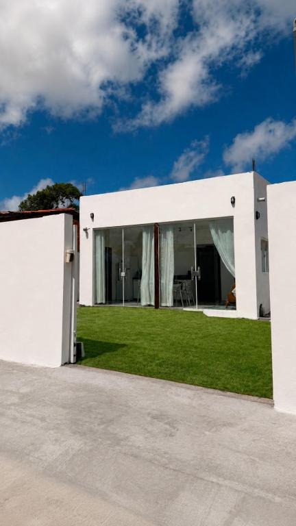 a white house with a lawn in front of it at Chalé Arandu in Santo Amaro