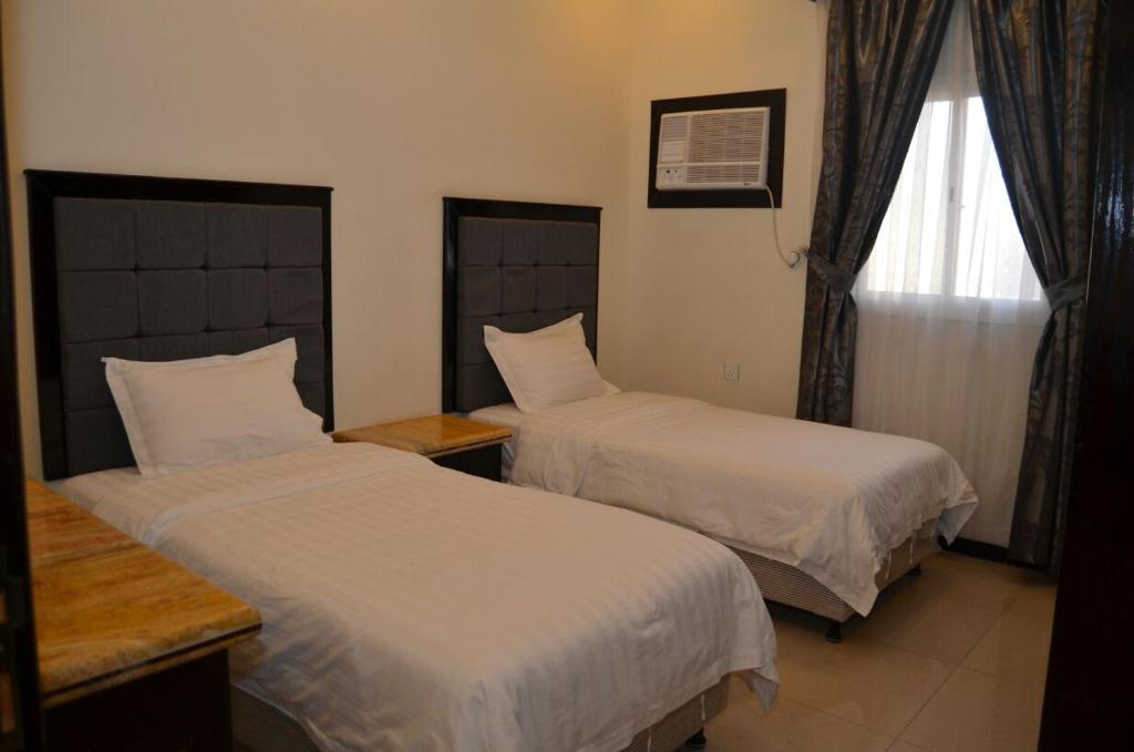 1 dormitorio con 2 camas y ventana en فخامة الديار للشقق المخدومة Fakhamat Aldyar For Serviced Apartments, en Taif