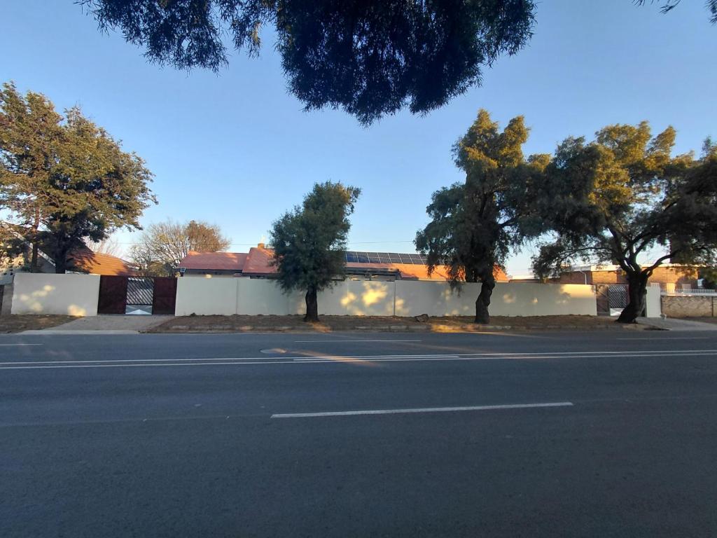 an empty parking lot with trees in front of a building at The Lantern Porch Guesthouse in Vryburg