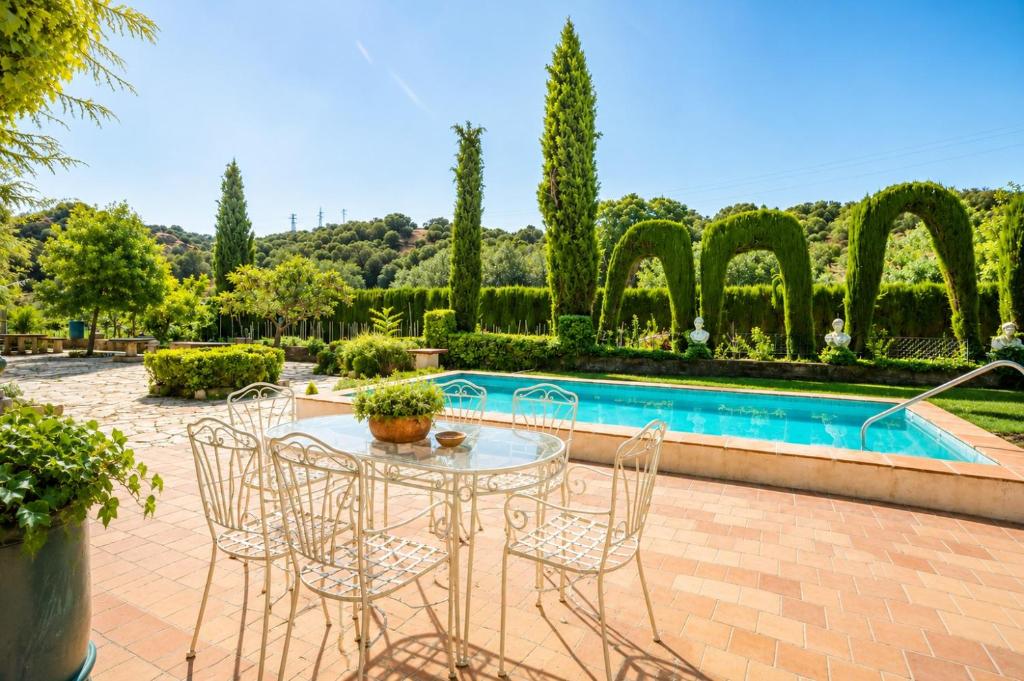 a patio with a table and chairs and a pool at Molino de Búlar - 1920 Olive Oil Mill Heritage in Piñar