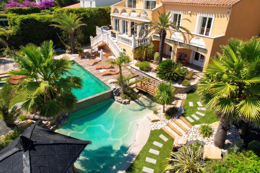 an aerial view of a house with a swimming pool and palm trees at Villa Halo Lagoon Pool & Exclusive seaside getaway in Cap d'Agde