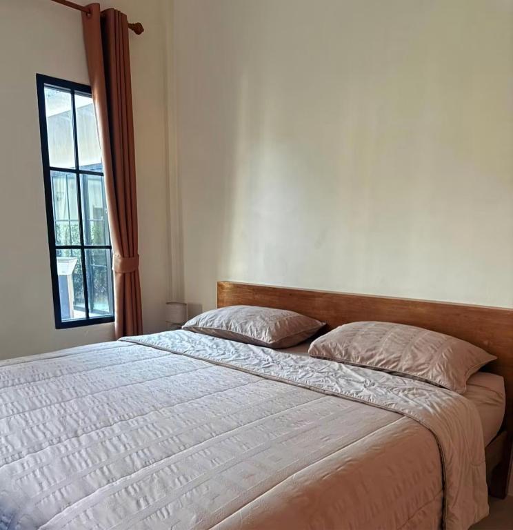 a bedroom with a large bed with a window at Langbaan cafe and homestay in Ban Mai