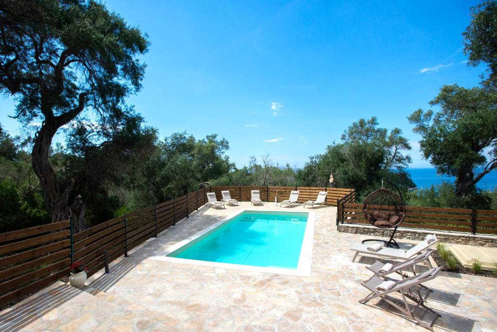a swimming pool with chaise lounge chairs and a fence at Villa Praxithea in Lákka