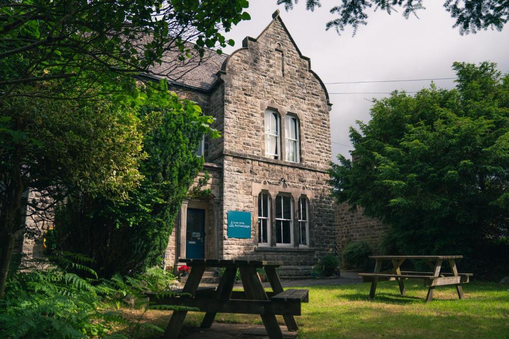 two picnic tables in front of a brick building at Base Camp Hathersage, YHA Partner in Hathersage