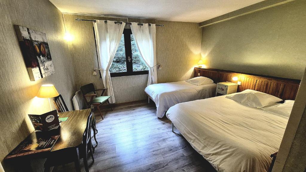 a hotel room with two beds and a desk at Le Terminus in Ax-les-Thermes