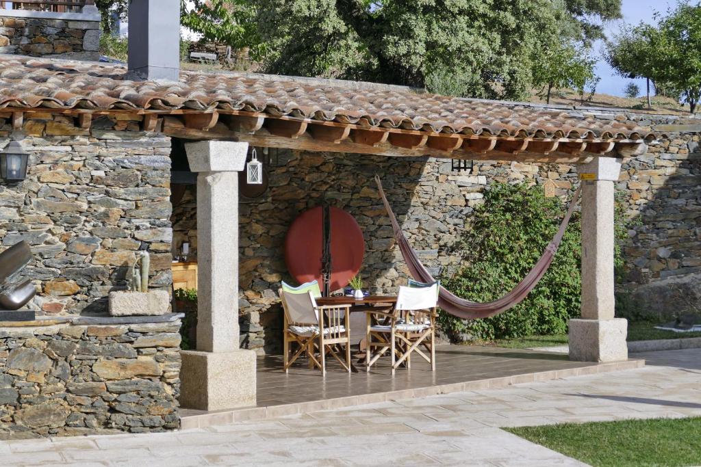 a patio with a hammock and a table and chairs at Casa das Quintas in Quinta das Quebradas
