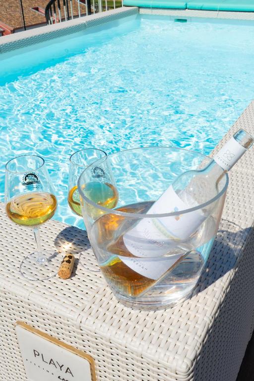 a glass of wine and wine glasses on a table next to a swimming pool at Almarea Cirò Marina in Cirò Marina