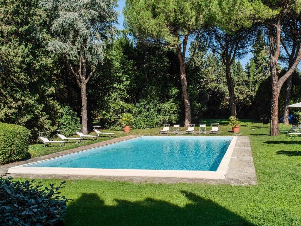 a swimming pool with chaises and chairs in a yard at B&B HOTEL Calenzano First in Calenzano